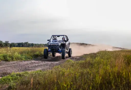 Polaris RZR kicking up dust on a dirt trail